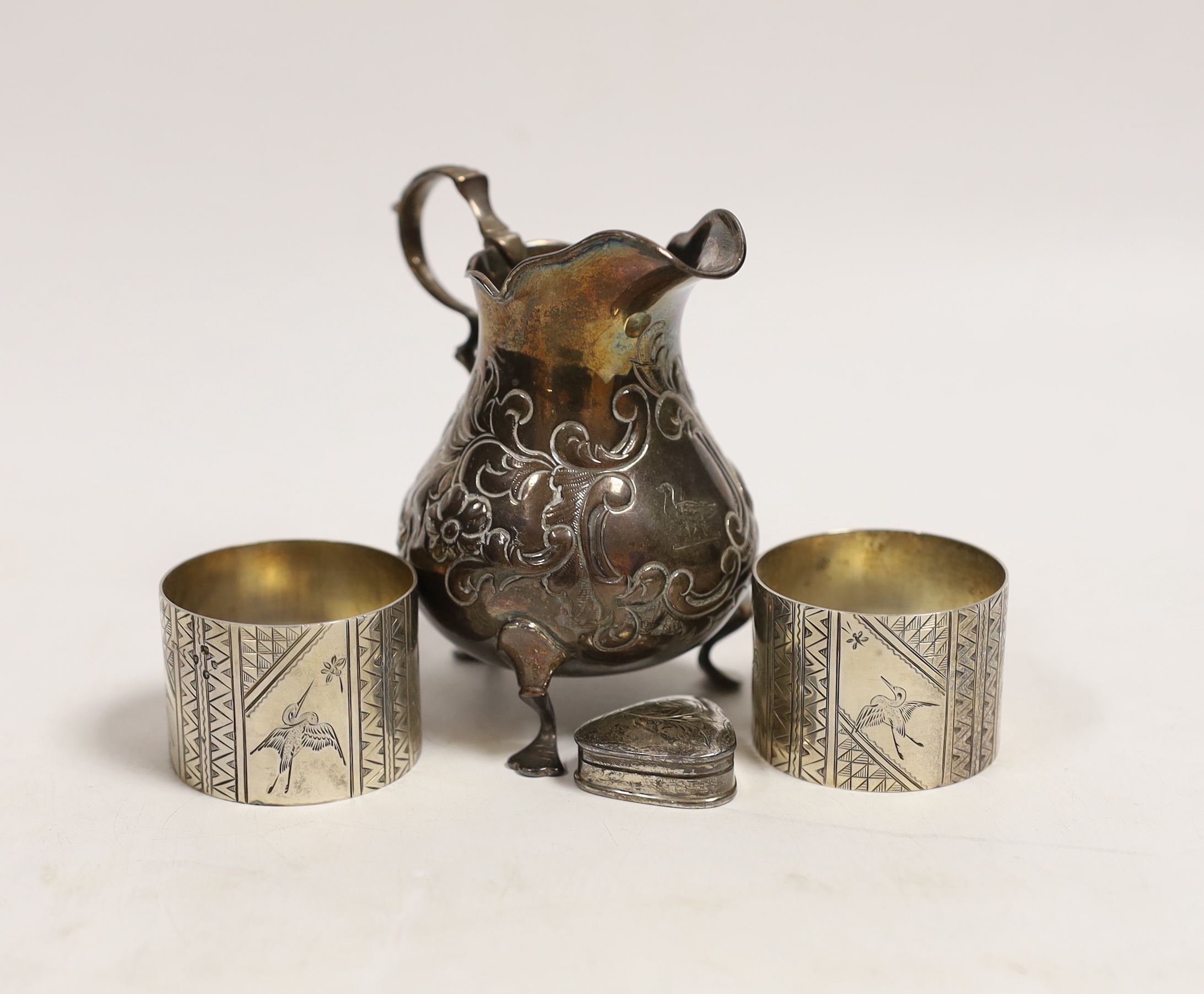 A Victorian silver baluster cream jug, London, 1846, 95mm, a pair of Victorian silver napkin rings engraved with aesthetic decoration, Charles Edwards, London, 1880 and a modern silver pill box.